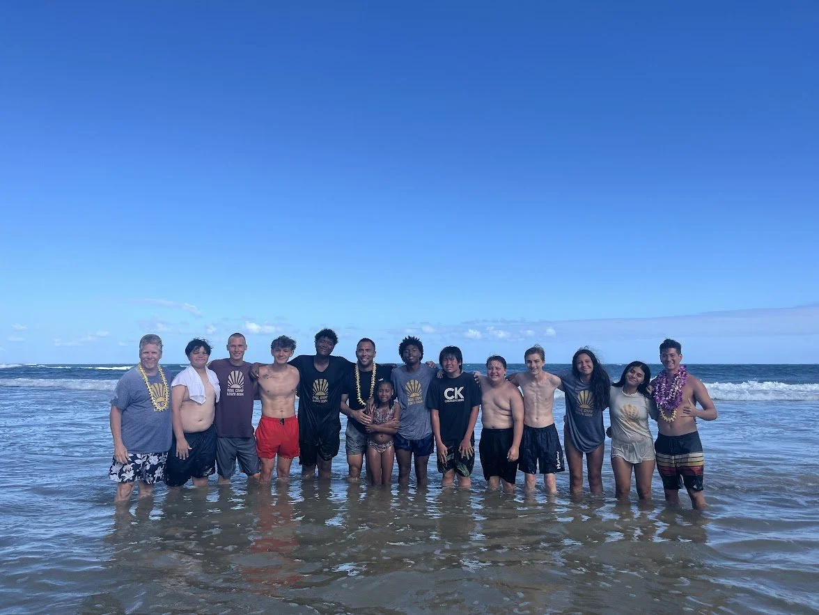 Overcome campers standing together in the ocean in Kauai